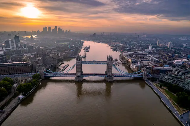 An aerial view of Tower Bridge and the Thames at sunrise.